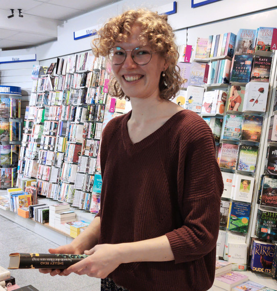 Carla Debbeler holding a book in a bookstore in her hands 