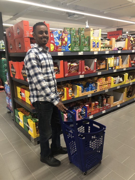 Abel Kebede Reda pushing a shopping basket in a grocery store