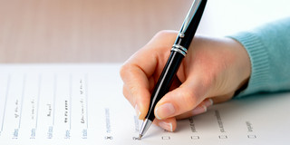 Survey A hand holding a pen fills out a survey questionnaire.